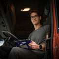 Man sitting inside a vehicle holding a tachograph equipment.